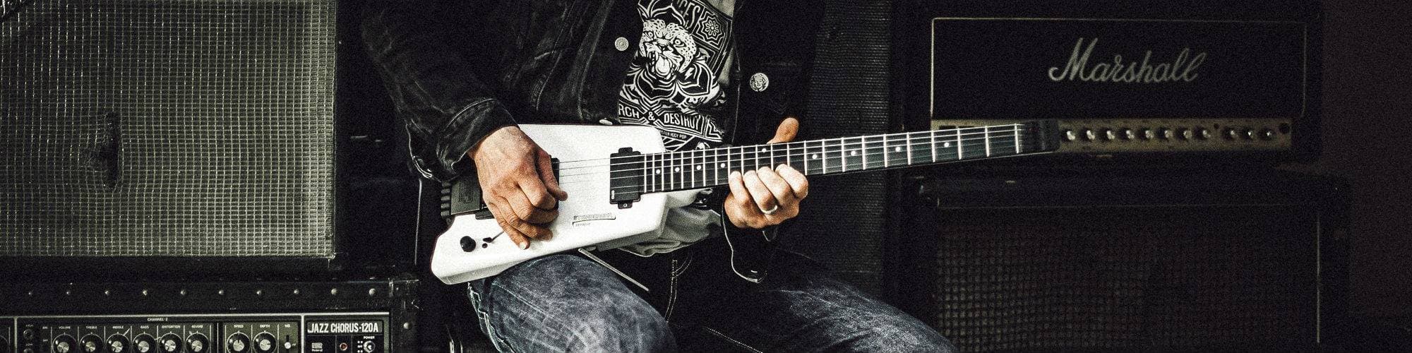 A guitarist sat playing on some amps