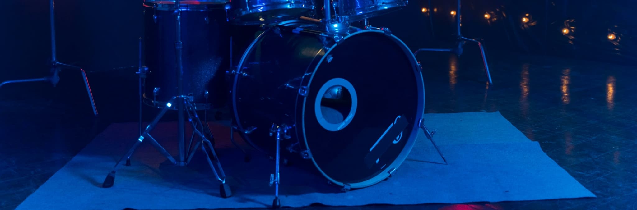Drummer playing a drum kit with vibrant lighting.