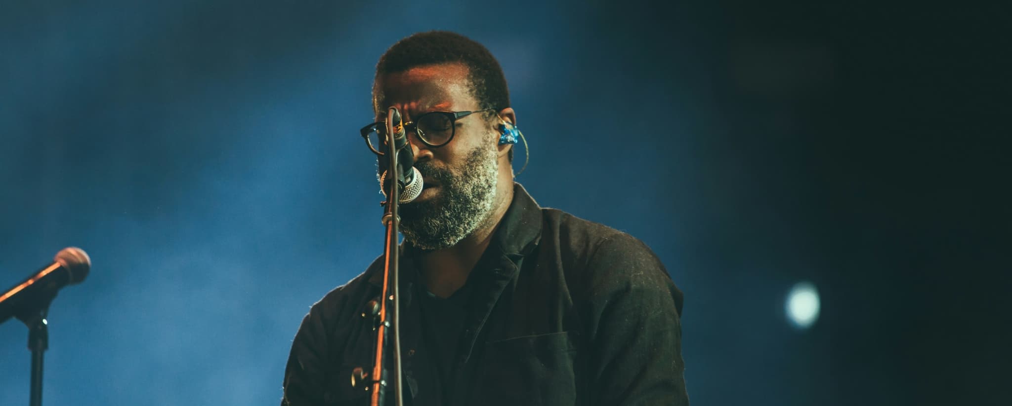 A musician performing on stage with a microphone and electronic instrument.